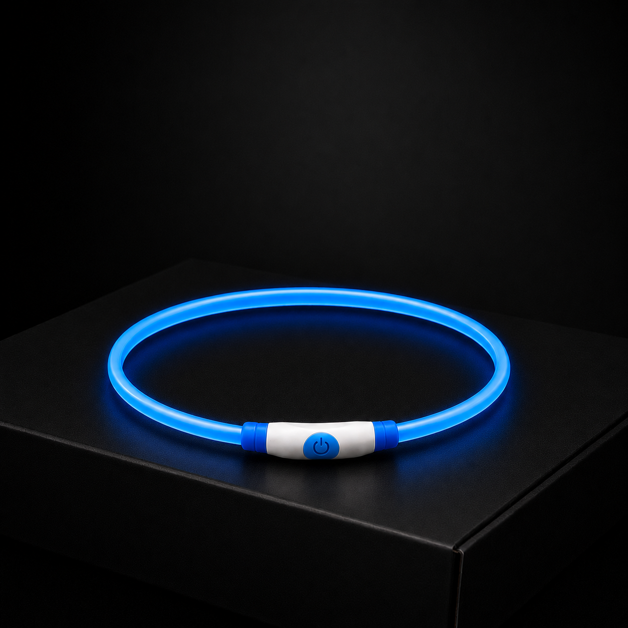 Blue LED dog collar on a black surface with a dark background