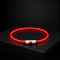 Red glowing necklace on a black surface with a dark background