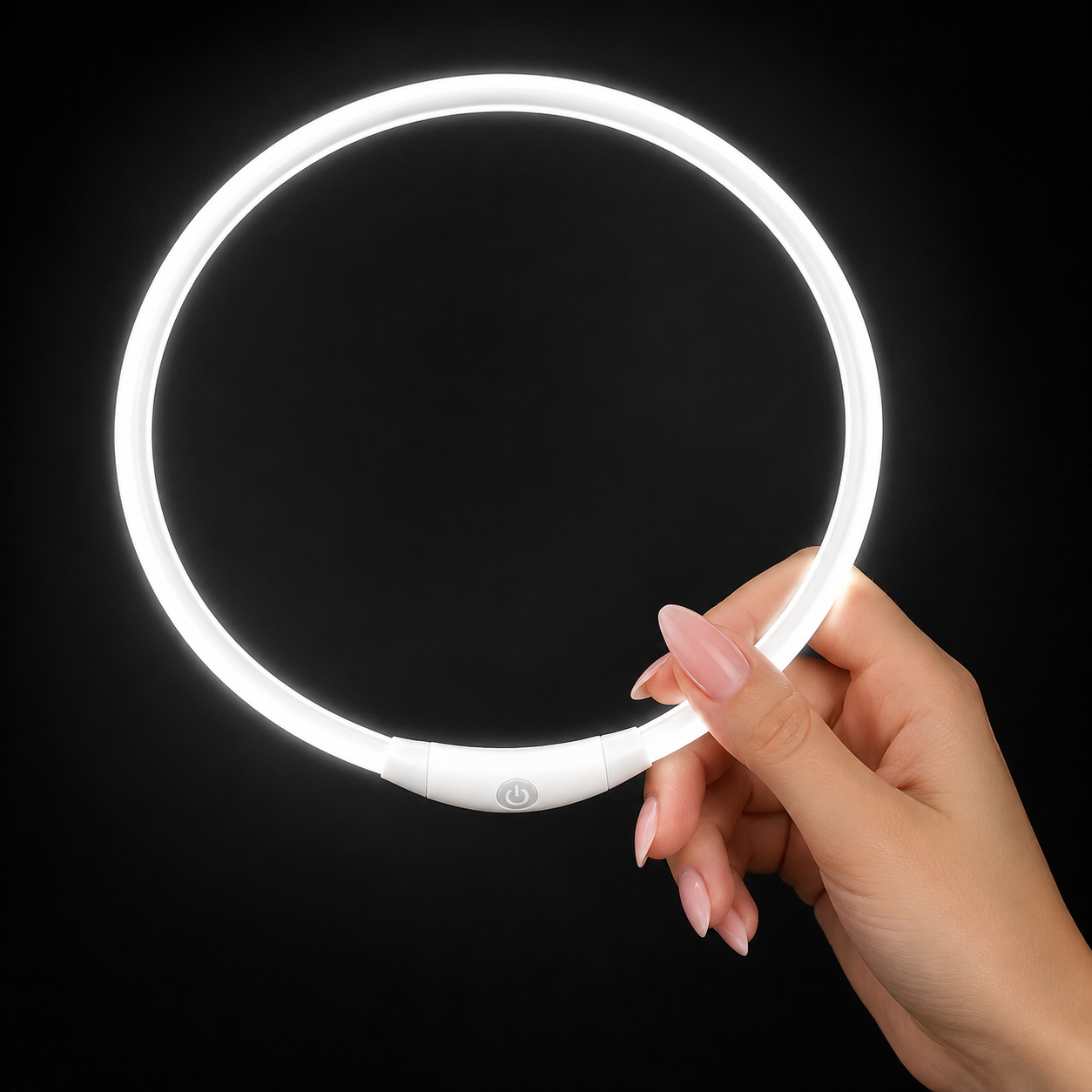 Hand holding a white LED ring light against a black background